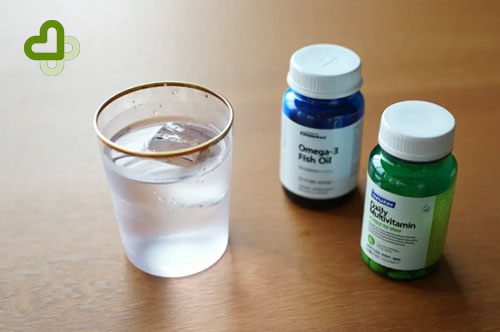 Витамины и стакан воды на столе